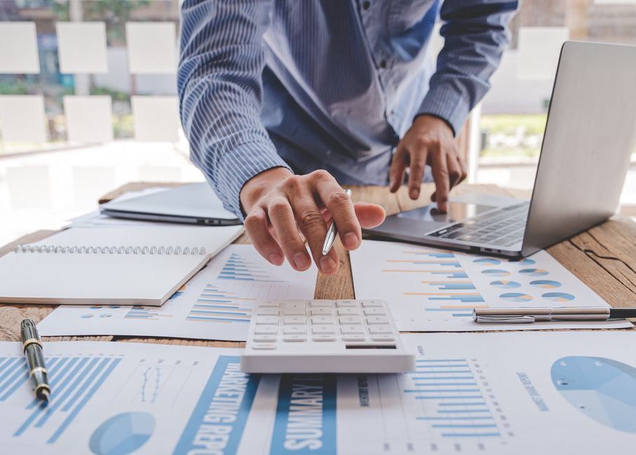 Professional conducting valuation calculation with charts and laptop.