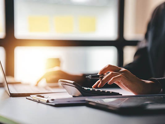 Portrait of a woman working on a tablet computer in a modern off Business immigration consultant working on laptop with calculator