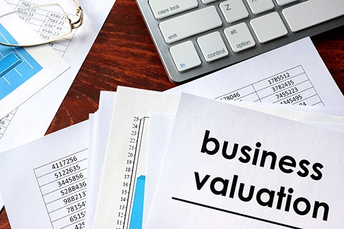 Business valuation written in a document and business charts. Desk with documents for business immigration valuation