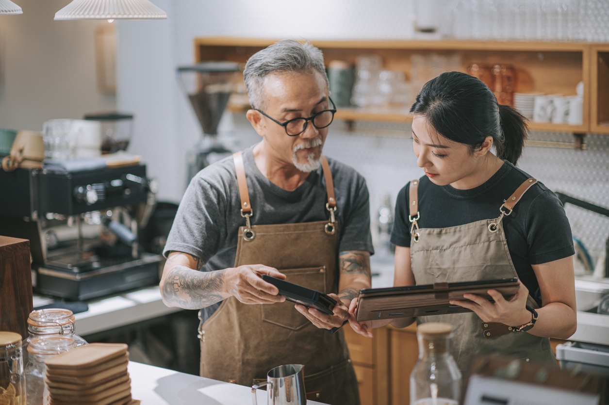 Senior passing tablet to junior in family business discussion