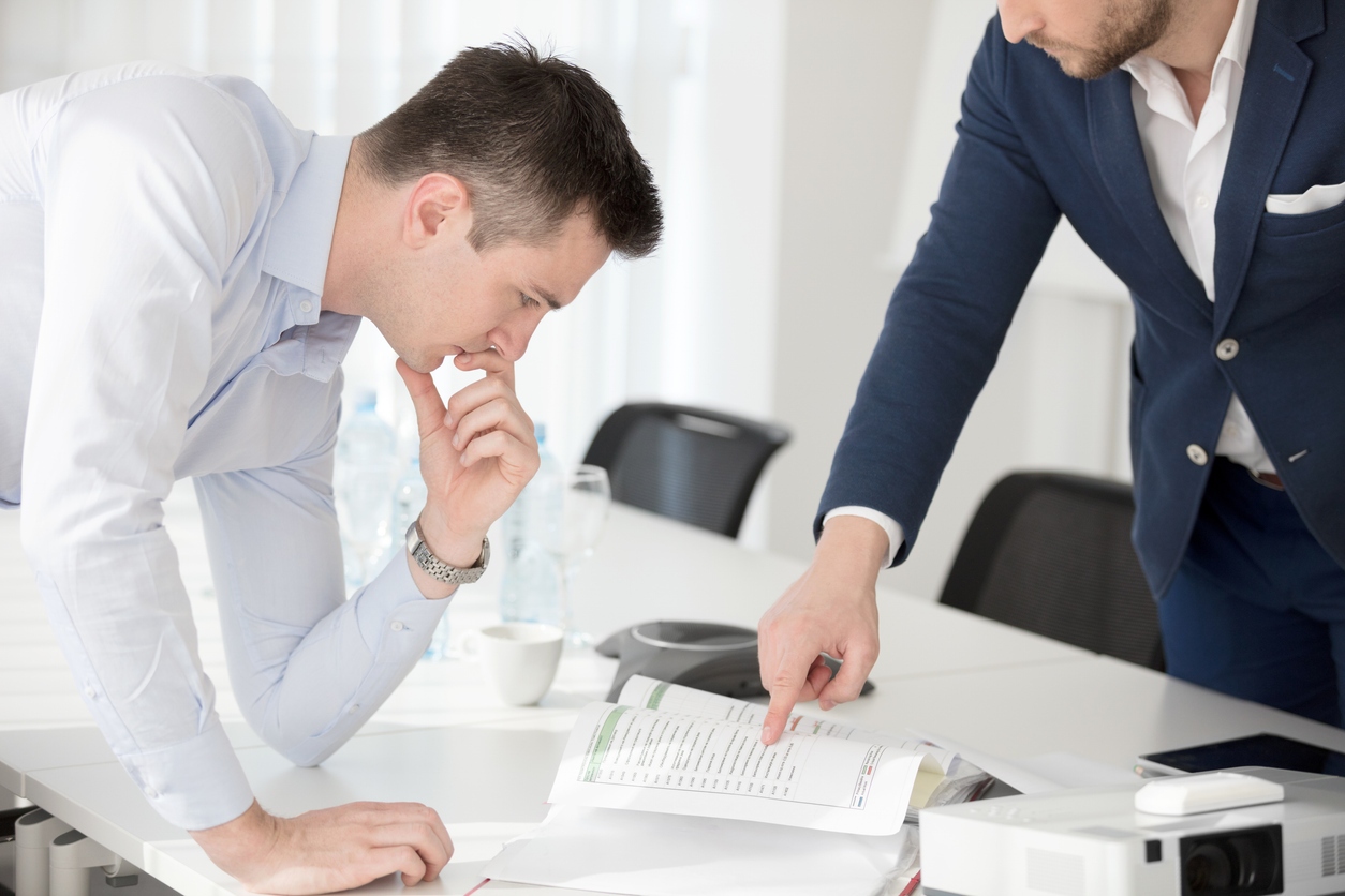 Businessmen reviewing a business valuation report in office.