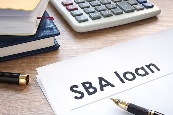 SBA loan form on an office table. Close-up view of a document titled 'SBA loan' with a calculator and fountain pen, symbolizing venture financing and financial planning for maximizing SBA loan benefits